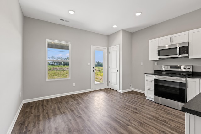 kitchen with appliances with stainless steel finishes, dark hardwood / wood-style floors, and white cabinets