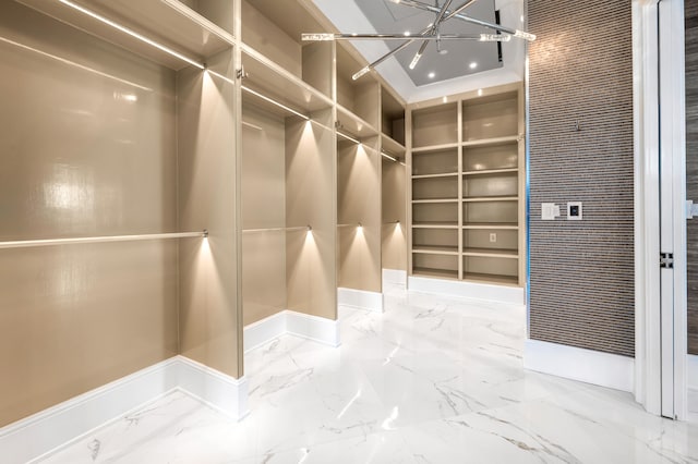 spacious closet with an inviting chandelier and light tile flooring