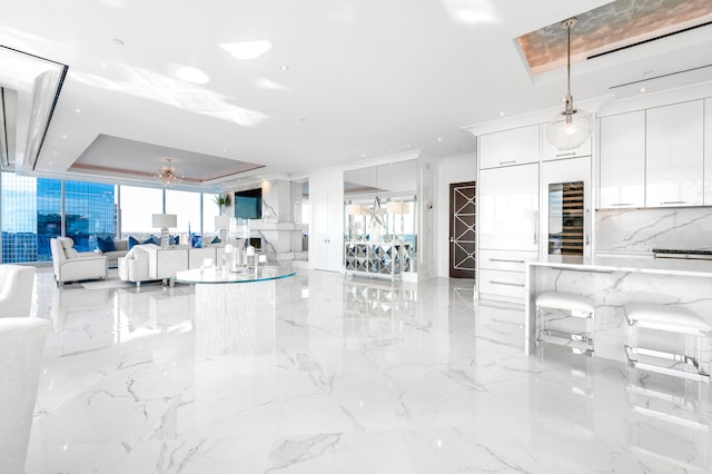 interior space with white cabinetry, pendant lighting, light tile floors, and a raised ceiling