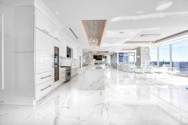 kitchen with stainless steel stove, white cabinets, light stone counters, decorative light fixtures, and light tile floors