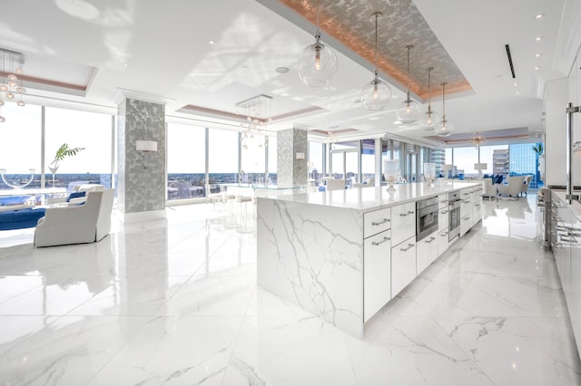 kitchen featuring a tray ceiling, white cabinetry, a spacious island, and light tile floors