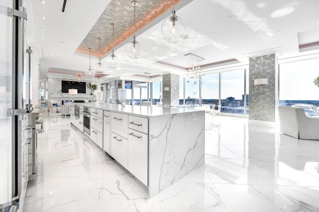 kitchen featuring pendant lighting, a raised ceiling, a large island, and white cabinetry