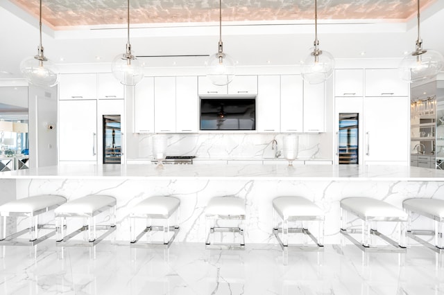 kitchen featuring white cabinets, a breakfast bar area, and hanging light fixtures