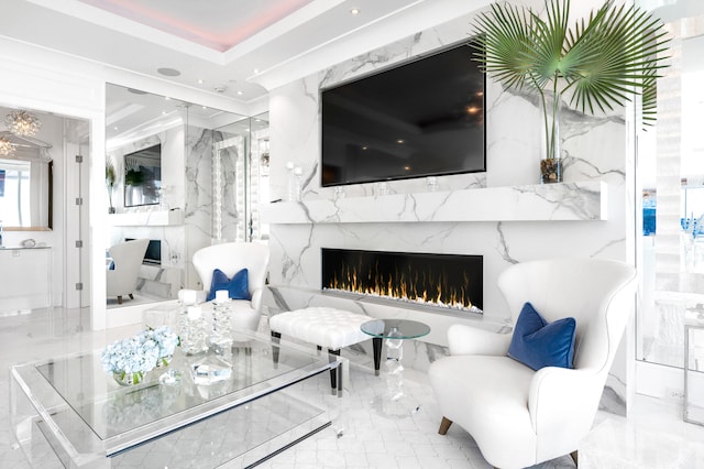 living room featuring tile floors, a high end fireplace, and a tray ceiling