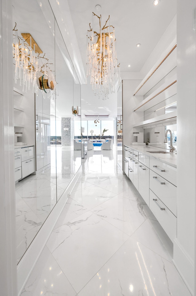 interior space with white cabinets, sink, a chandelier, and light tile floors