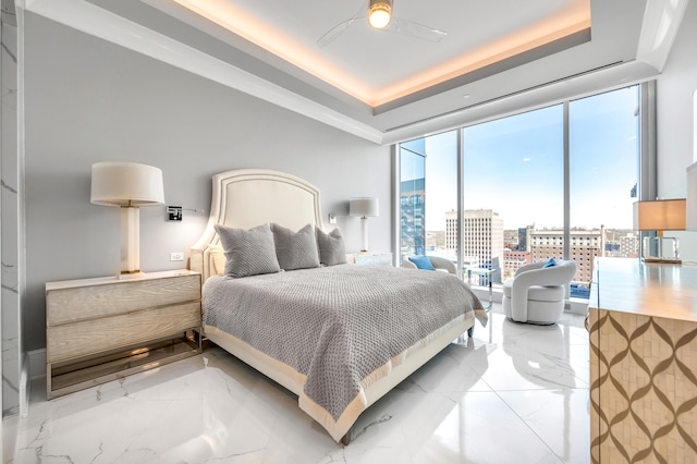 tiled bedroom with a tray ceiling, ceiling fan, and a wall of windows