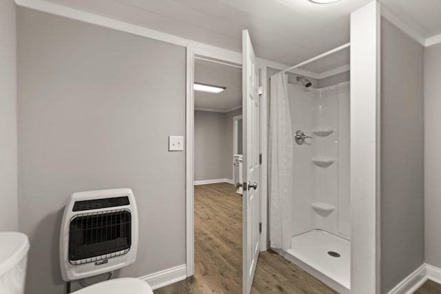 bathroom with wood-type flooring, a shower with shower curtain, toilet, and ornamental molding