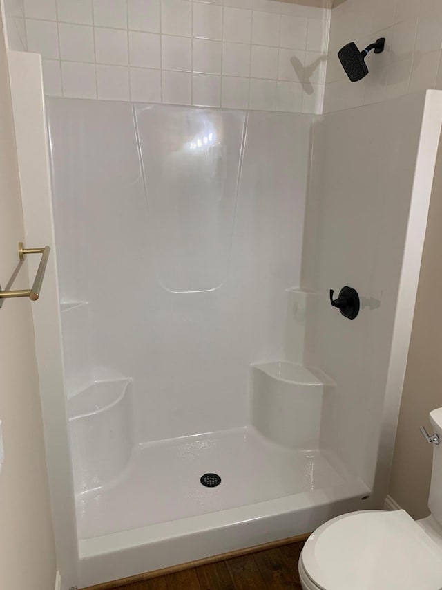 bathroom featuring hardwood / wood-style floors, toilet, and a tile shower