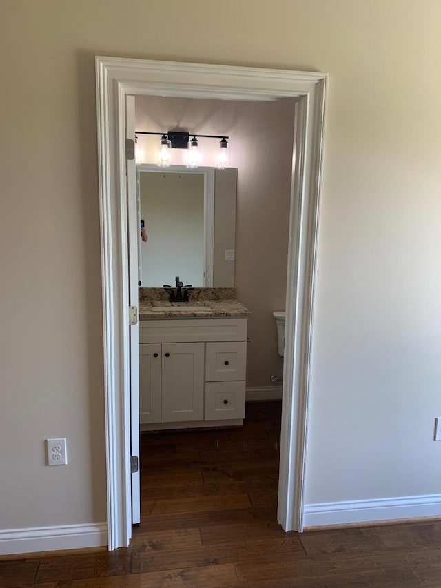 bathroom featuring toilet, hardwood / wood-style flooring, and vanity