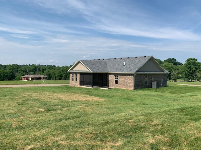 rear view of property with a lawn and central air condition unit