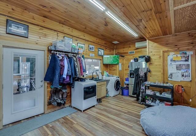 interior space featuring washer / dryer, a wall mounted AC, sink, and light hardwood / wood-style floors