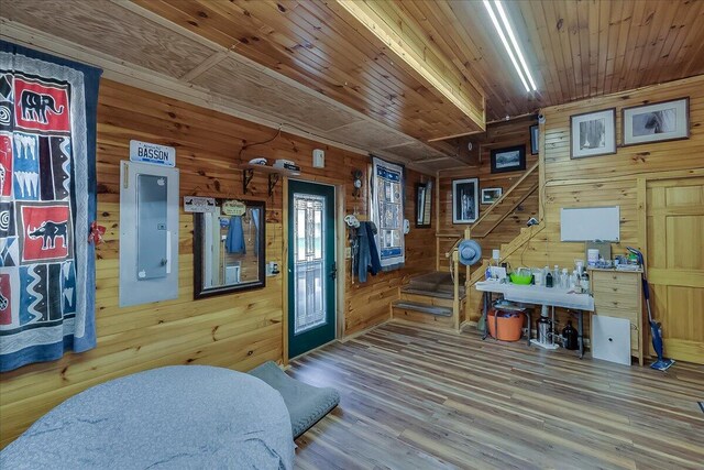 interior space featuring wood-type flooring, electric panel, wooden walls, and wooden ceiling