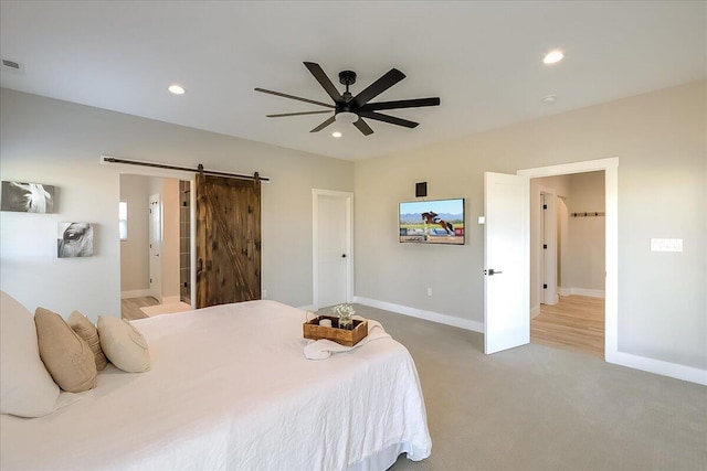 bedroom featuring connected bathroom, a barn door, ceiling fan, and carpet flooring