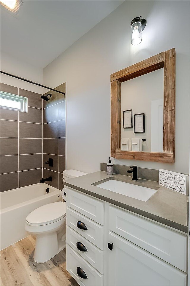 full bathroom featuring hardwood / wood-style floors, vanity, toilet, and tiled shower / bath