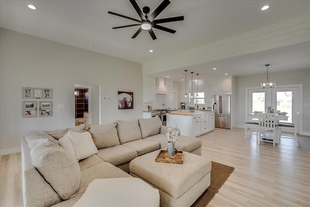 living room with light hardwood / wood-style floors and ceiling fan with notable chandelier