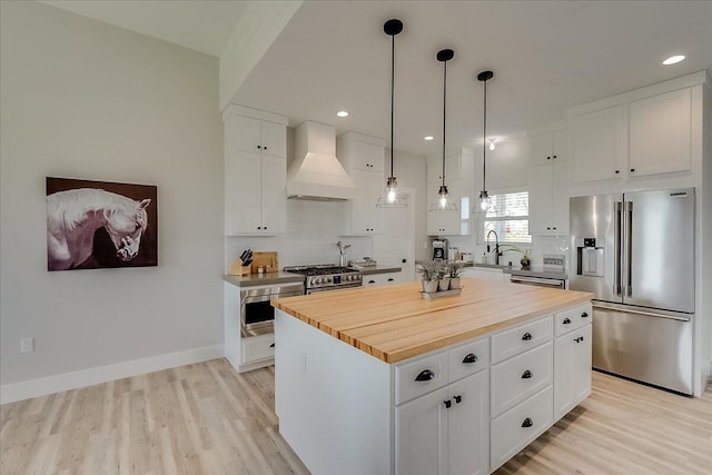 kitchen featuring custom exhaust hood, white cabinets, decorative light fixtures, a kitchen island, and stainless steel appliances