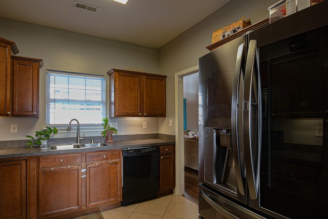 kitchen featuring stainless steel fridge, sink, light tile patterned flooring, and black dishwasher