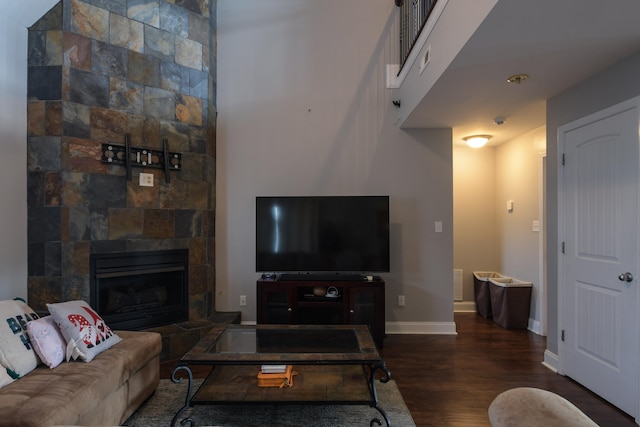 living room with a tile fireplace and dark hardwood / wood-style flooring