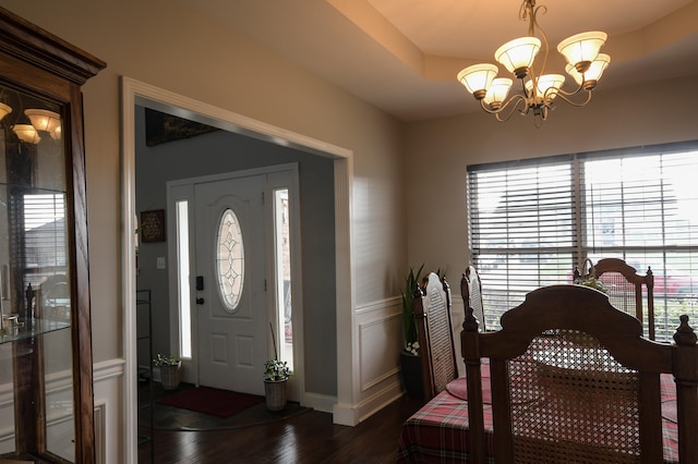 entryway featuring a raised ceiling, a wealth of natural light, dark hardwood / wood-style flooring, and a chandelier