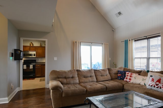 living room with dark hardwood / wood-style floors, high vaulted ceiling, and plenty of natural light