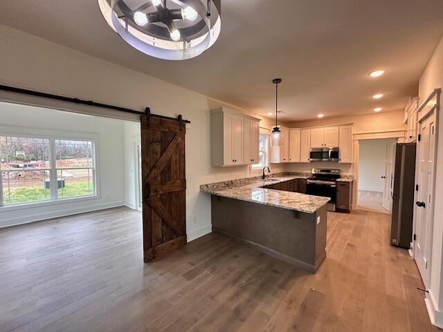 kitchen featuring white cabinetry, decorative light fixtures, light hardwood / wood-style floors, kitchen peninsula, and stainless steel appliances