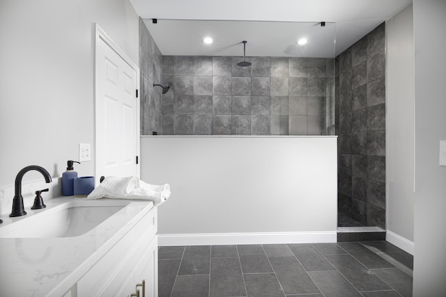 bathroom featuring a tile shower, tile patterned flooring, and vanity