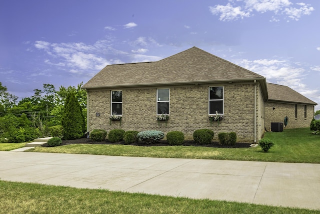 view of side of property with a lawn and central AC unit