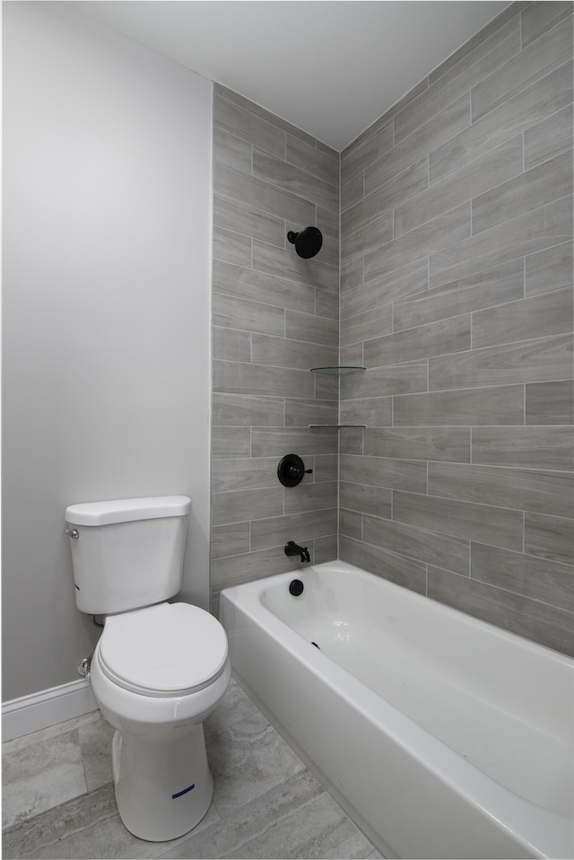 bathroom with toilet and tiled shower / bath