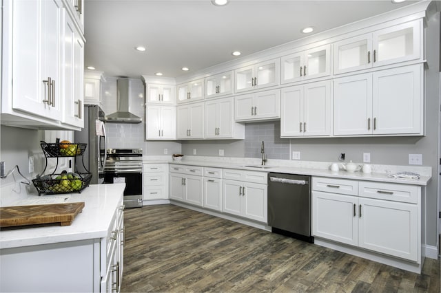 kitchen featuring light stone counters, stainless steel appliances, sink, wall chimney range hood, and white cabinets