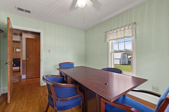 office featuring a ceiling fan, baseboards, visible vents, and wood finished floors