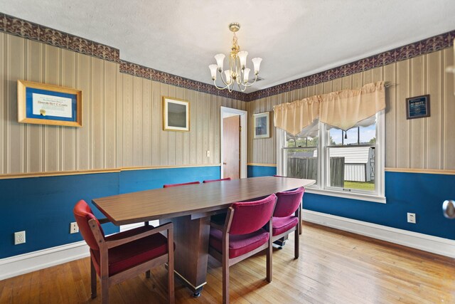 dining room featuring baseboards, wood finished floors, a chandelier, and wallpapered walls