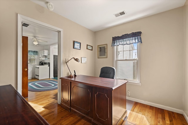 home office with visible vents, light wood-style floors, ceiling fan, and baseboards