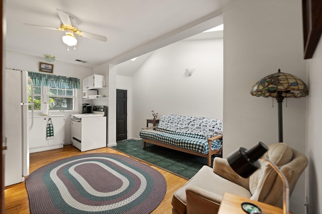 living area with a ceiling fan, visible vents, vaulted ceiling, and light wood-type flooring