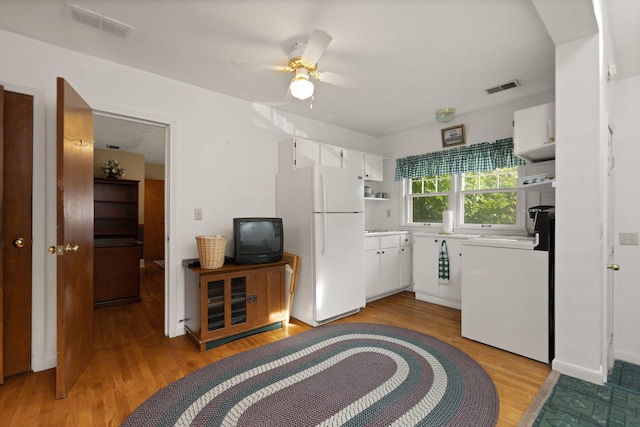 kitchen featuring white cabinets, freestanding refrigerator, light wood-type flooring, and visible vents