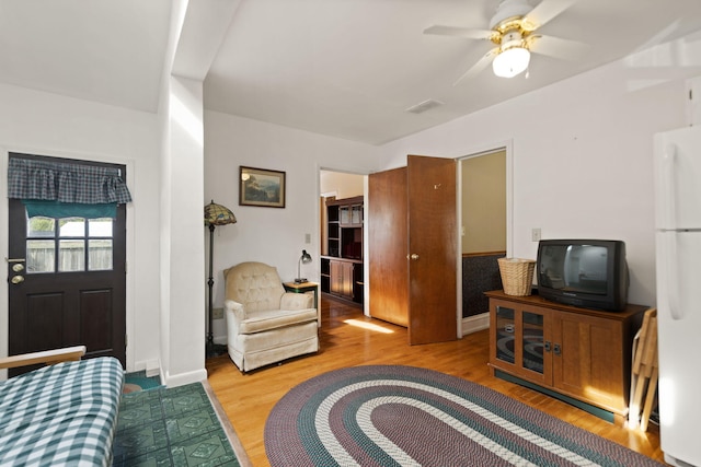 living room featuring a ceiling fan, visible vents, and wood finished floors