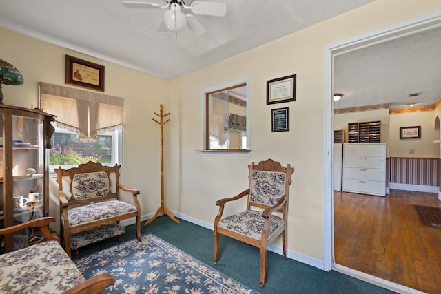 sitting room with ceiling fan and dark wood-type flooring