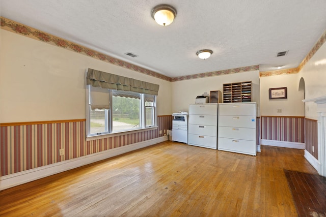 unfurnished bedroom featuring visible vents, a textured ceiling, and hardwood / wood-style flooring
