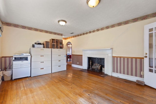 interior space with arched walkways, a fireplace, and hardwood / wood-style flooring