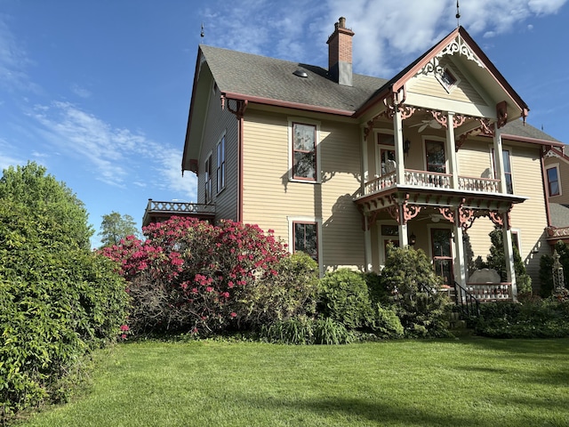 1023 Riverside Dr, Greenup, KY 41144 - back of house featuring a chimney, a balcony, a lawn, and a shingled roof