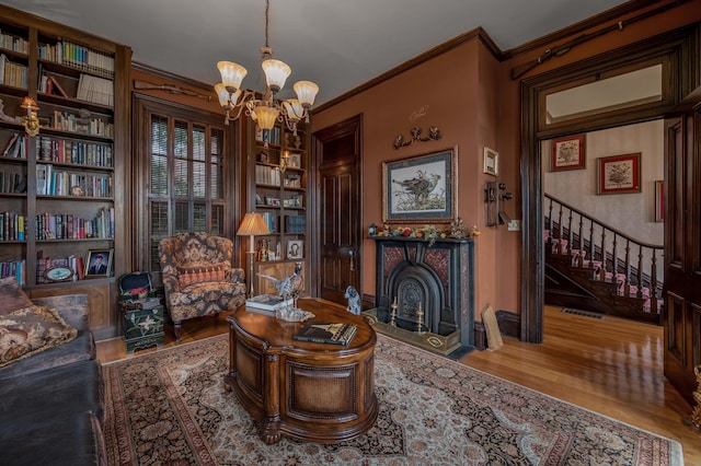 1023 Riverside Dr, Greenup, KY 41144 - living area featuring wood finished floors, a chandelier, ornamental molding, stairs, and a fireplace with flush hearth