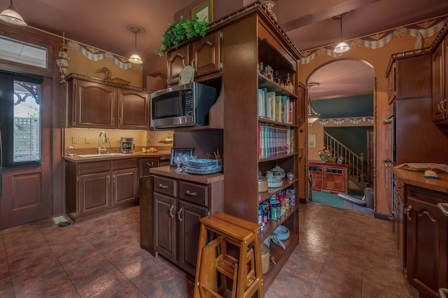 1023 Riverside Dr, Greenup, KY 41144 - kitchen featuring stainless steel microwave, a sink, arched walkways, open shelves, and decorative light fixtures