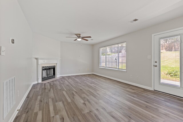 unfurnished living room featuring a fireplace, wood finished floors, and visible vents