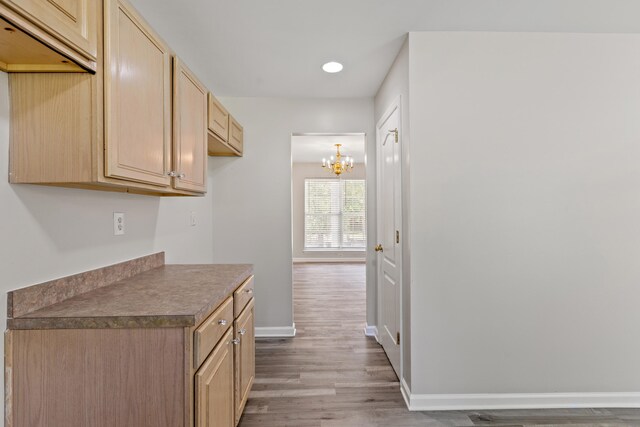 kitchen with baseboards, wood finished floors, an inviting chandelier, light brown cabinets, and recessed lighting