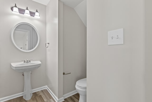 half bath featuring baseboards, toilet, and wood finished floors