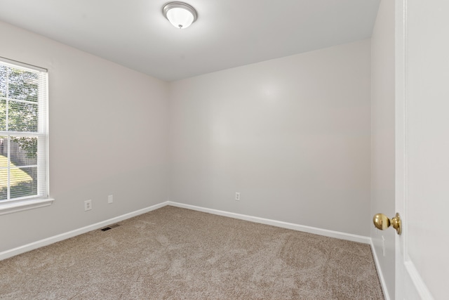 carpeted spare room featuring visible vents and baseboards