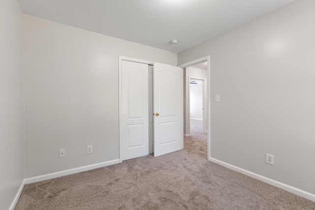 unfurnished bedroom with carpet floors, baseboards, and a closet