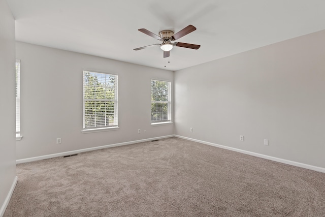 unfurnished room featuring carpet flooring, ceiling fan, visible vents, and baseboards