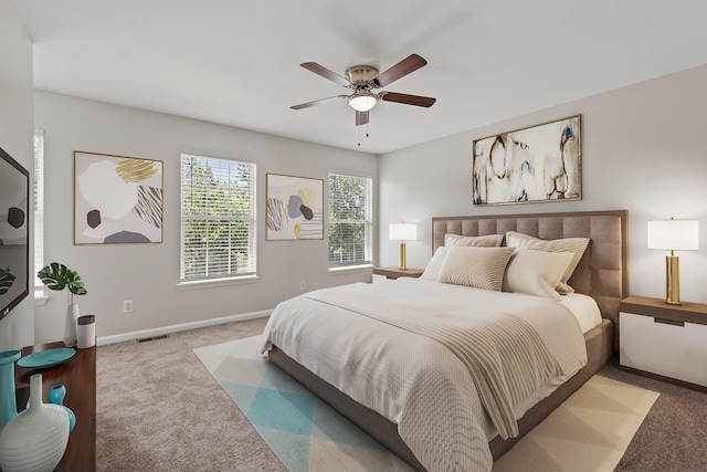 carpeted bedroom with a ceiling fan, visible vents, and baseboards