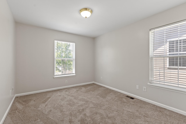 empty room with carpet flooring, visible vents, and baseboards