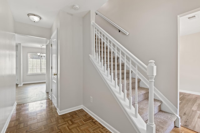 stairway featuring visible vents, baseboards, and a chandelier